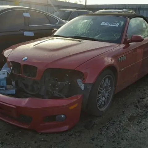 Red BMW M3 convertible parked in a yard, seen from the front quarter