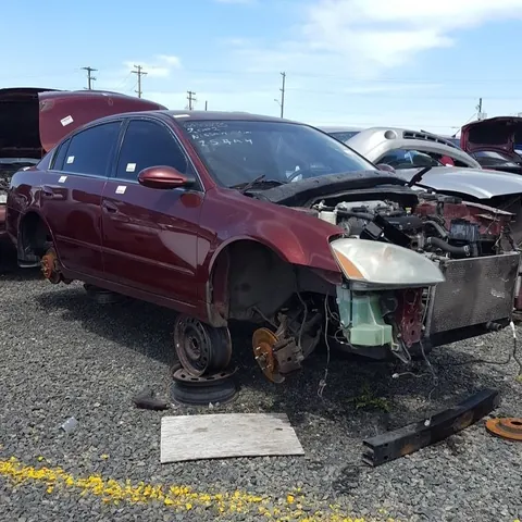 Dark red sedan with the front end stripped, in a breaker's yard